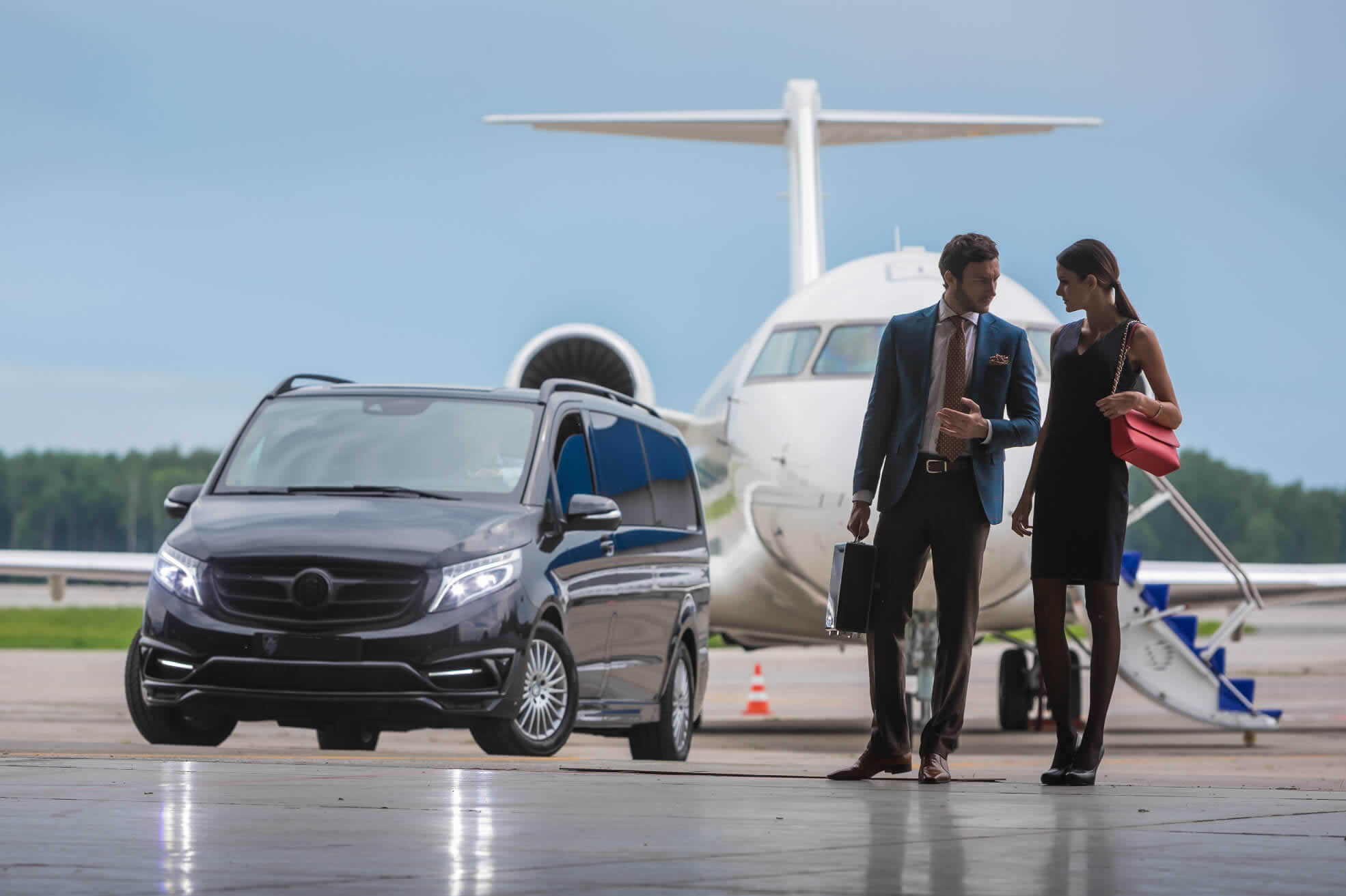 Business travelers with chauffeur-driven Mercedes V-Class beside a private jet
