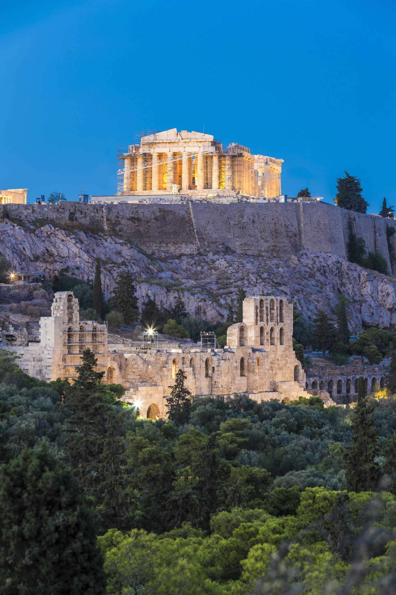 Evening view of the Acropolis in Athens, with the Parthenon and the Odeon of Herodes Atticus lit above the city.