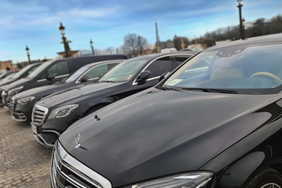 Fleet of luxury black Mercedes cars from CTP Limo parked in a row outdoors, with an urban background and blue sky.