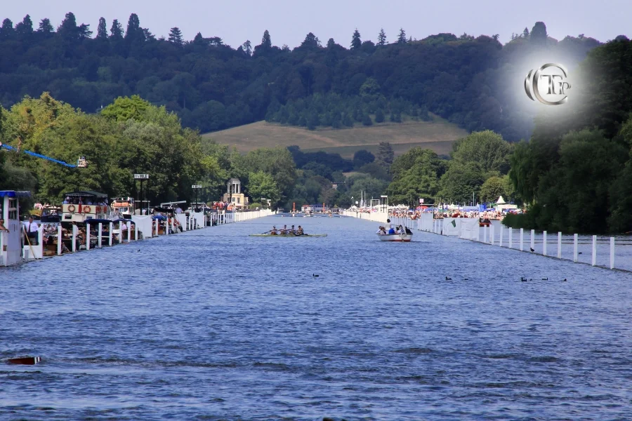 Équipes d’aviron en course sur la Tamise pendant le Henley Royal Regatta, avec des spectateurs sur les rives.