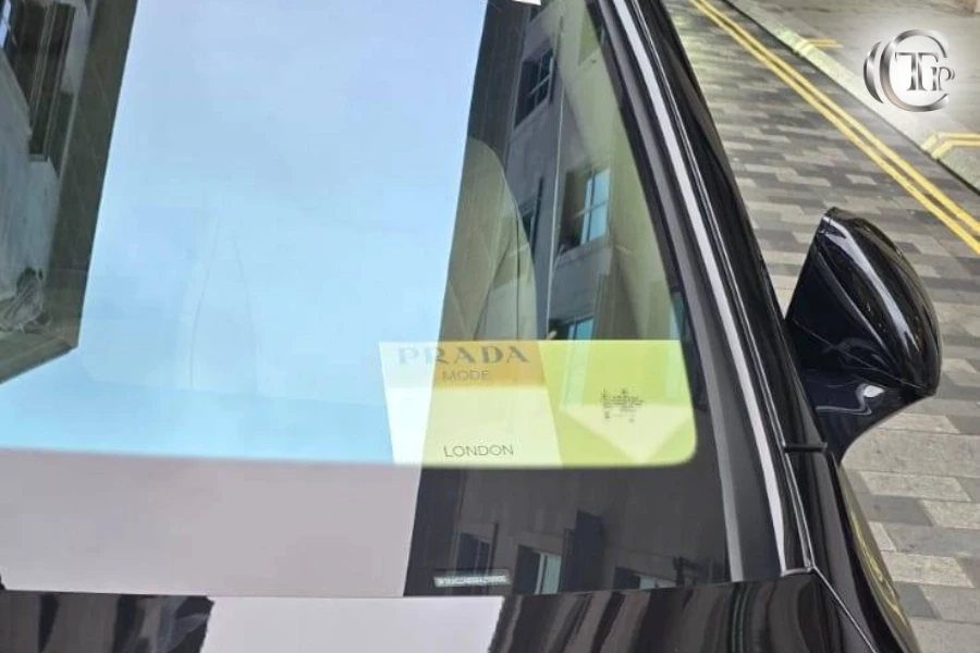 Luxury chauffeur car in London with Prada Mode event pass visible on the windshield.